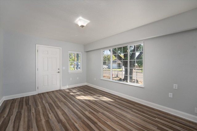 empty room featuring baseboards and dark wood-style flooring