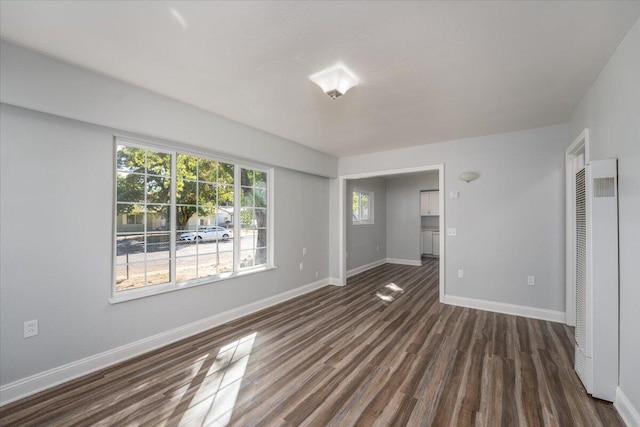 interior space featuring dark wood-style floors, a heating unit, and baseboards