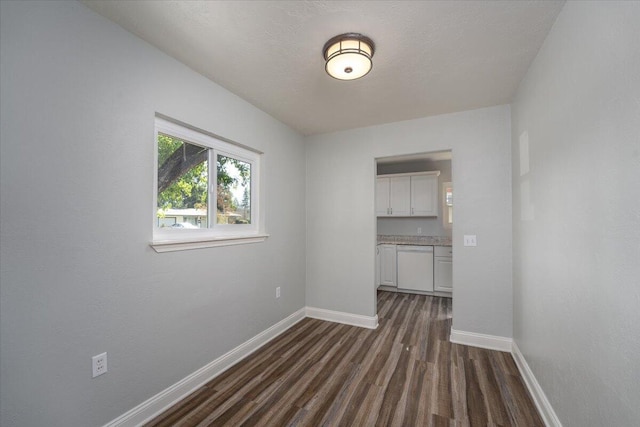 empty room featuring dark wood-style floors, a textured ceiling, and baseboards