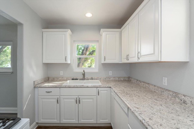 kitchen with dishwasher, light countertops, a sink, and white cabinets