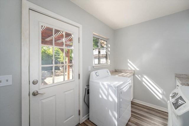 laundry area with baseboards, cabinet space, washing machine and clothes dryer, and wood finished floors