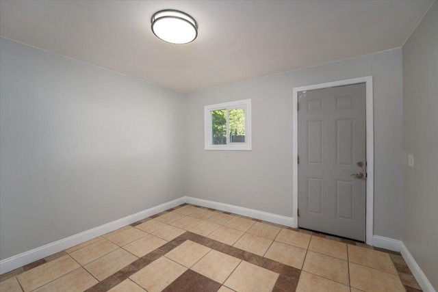 empty room with light tile patterned floors and baseboards