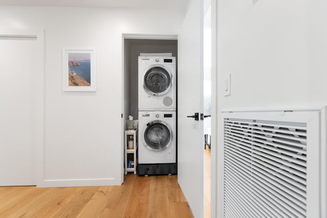 laundry area featuring laundry area, light wood-style floors, and stacked washer / drying machine