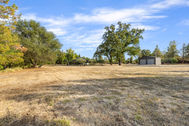 view of yard featuring a garage, a rural view, and an outdoor structure