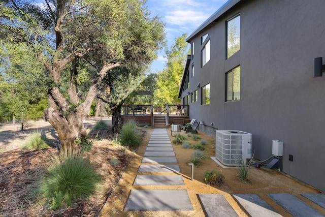 view of side of home featuring stairs, stucco siding, a deck, and central air condition unit