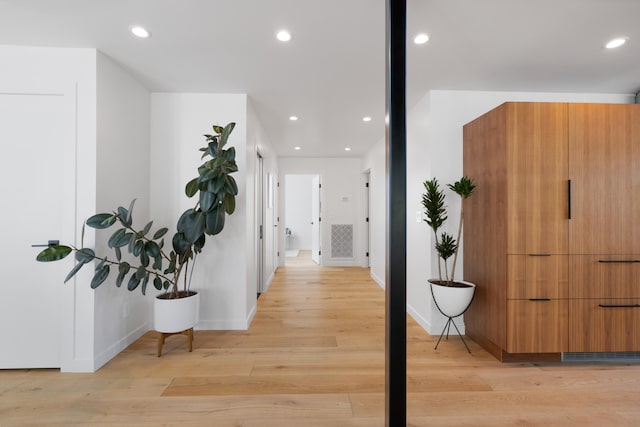 hall featuring light wood-style flooring, baseboards, and recessed lighting