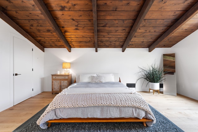 bedroom with lofted ceiling with beams, light wood-style floors, and wood ceiling