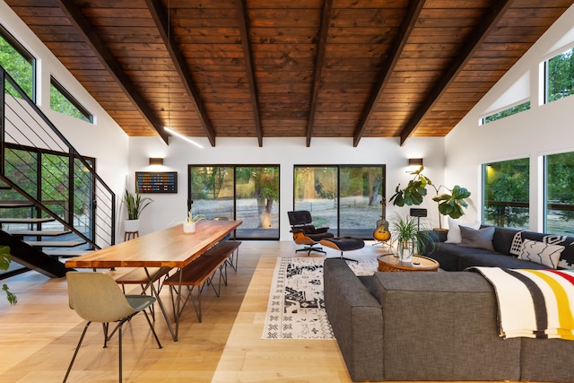 living room with beam ceiling, plenty of natural light, light wood finished floors, and stairs