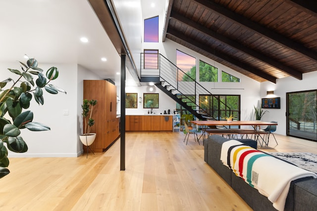 interior space with baseboards, wooden ceiling, light wood-style floors, high vaulted ceiling, and beam ceiling