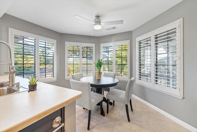 tiled dining area with ceiling fan and sink