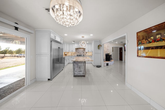 kitchen featuring light tile patterned floors, stainless steel appliances, decorative light fixtures, and a kitchen island