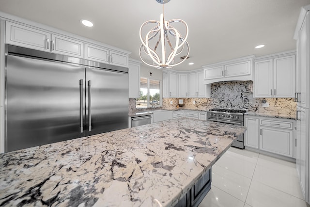 kitchen featuring hanging light fixtures, white cabinets, backsplash, an inviting chandelier, and high quality appliances