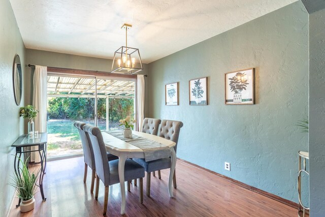 dining space with wood-type flooring and a notable chandelier