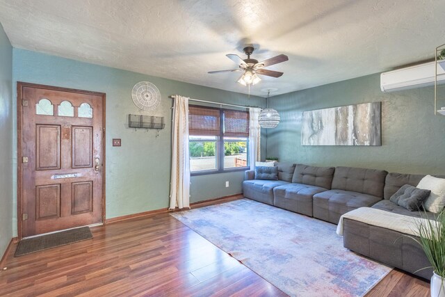 living room featuring a textured ceiling, an AC wall unit, ceiling fan, and hardwood / wood-style flooring