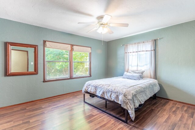 bedroom with multiple windows, dark hardwood / wood-style floors, and ceiling fan