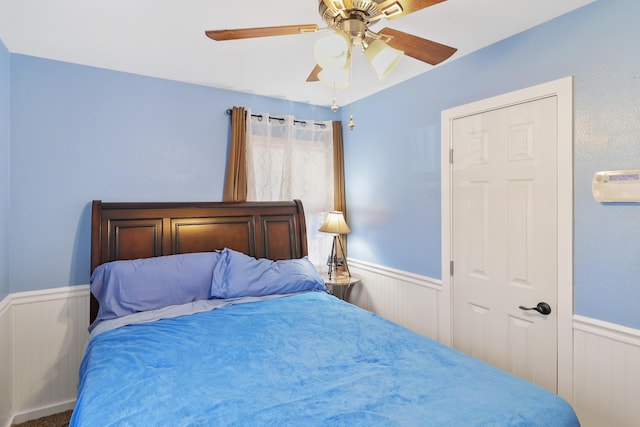 bedroom featuring a wainscoted wall and a ceiling fan