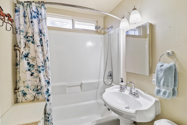 bathroom with shower / bathtub combination with curtain and a sink