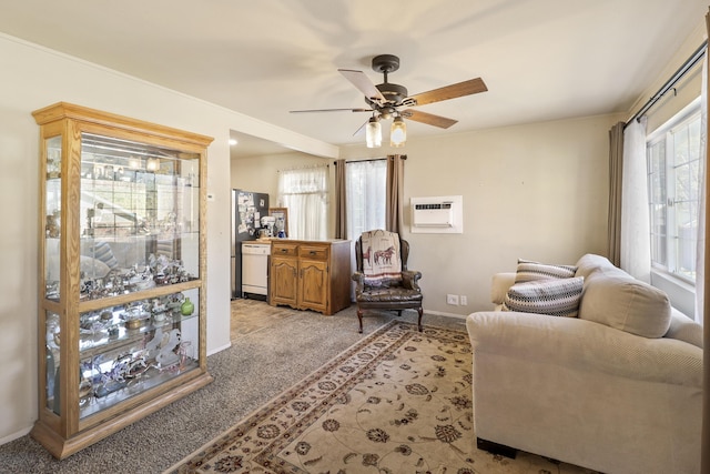 sitting room with baseboards, ceiling fan, a wall unit AC, and light colored carpet
