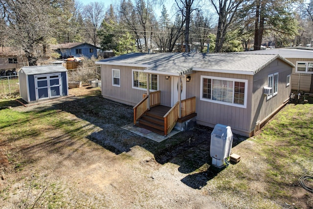rear view of house with an outbuilding, a shed, and fence