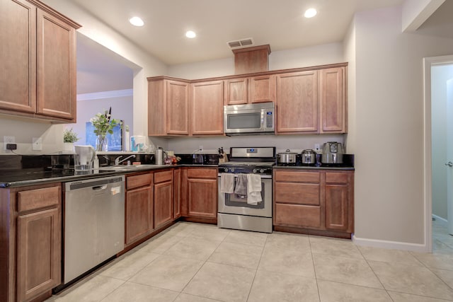 kitchen with light tile patterned floors, crown molding, sink, and stainless steel appliances