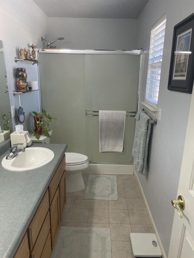 bathroom featuring vanity, tile patterned flooring, toilet, and an enclosed shower