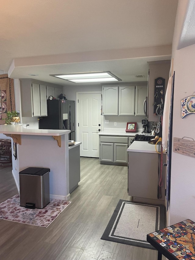 3471 Charles St, Cottonwood, CA 96022 - kitchen featuring light countertops, light wood-style flooring, refrigerator with ice dispenser, a peninsula, and a kitchen bar