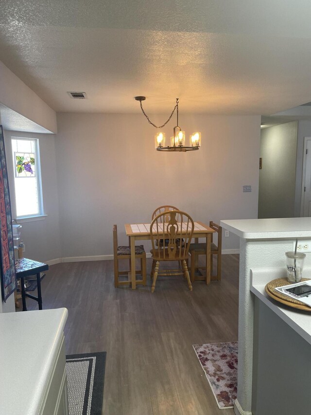 dining room featuring an inviting chandelier, a textured ceiling, and dark hardwood / wood-style flooring