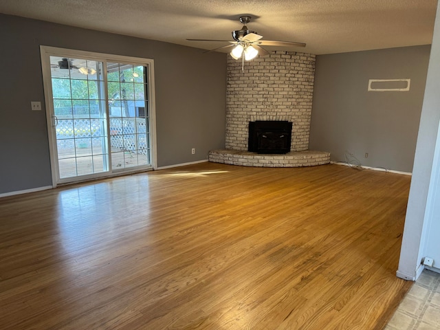 unfurnished living room featuring a fireplace, light hardwood / wood-style floors, a textured ceiling, and ceiling fan