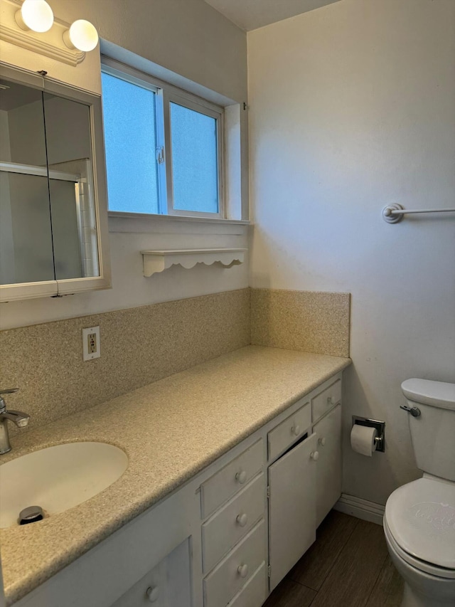 bathroom with toilet, vanity, an enclosed shower, and hardwood / wood-style flooring