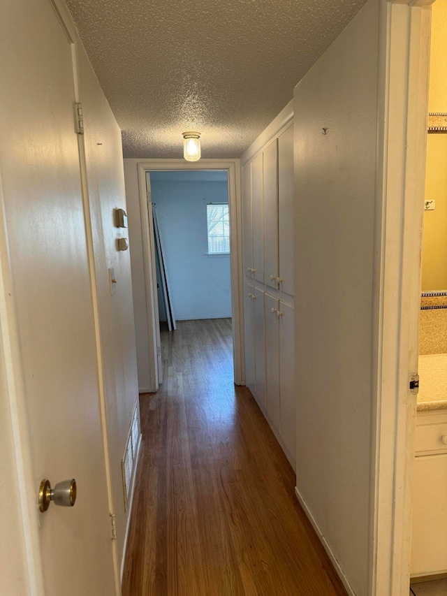 hallway featuring dark wood-type flooring and a textured ceiling