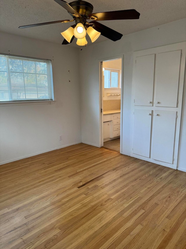 unfurnished bedroom featuring ensuite bathroom, ceiling fan, a textured ceiling, and light hardwood / wood-style flooring