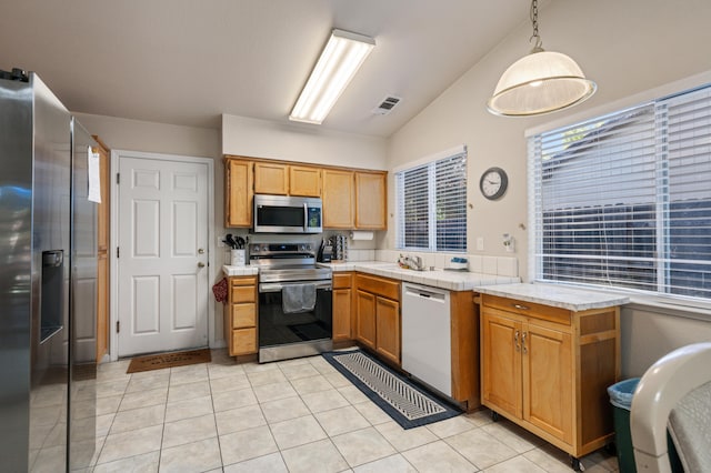 kitchen with light tile patterned flooring, vaulted ceiling, stainless steel appliances, decorative light fixtures, and sink