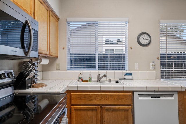 kitchen with sink, stainless steel appliances, and tile countertops