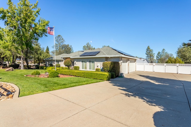 view of front of property featuring solar panels, a garage, and a front yard