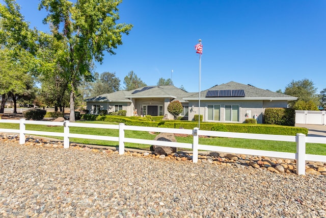 ranch-style home with solar panels and a front lawn