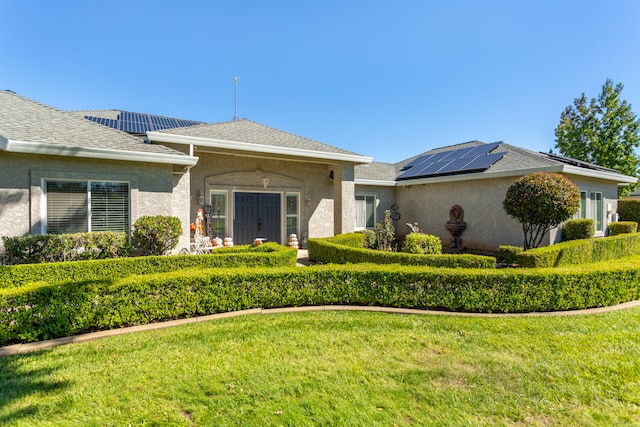 ranch-style home with solar panels and a front yard