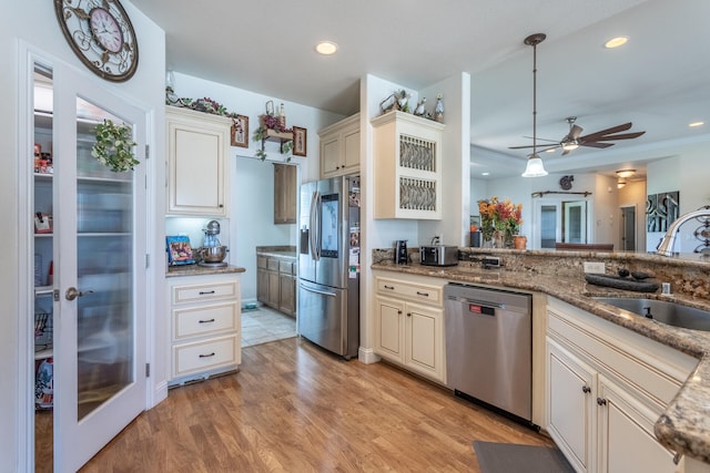 kitchen with sink, light hardwood / wood-style flooring, cream cabinets, pendant lighting, and appliances with stainless steel finishes