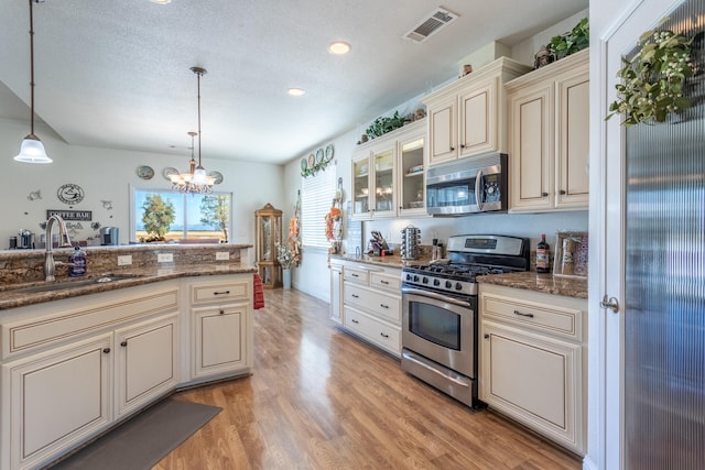 kitchen featuring sink, hanging light fixtures, an inviting chandelier, cream cabinets, and appliances with stainless steel finishes