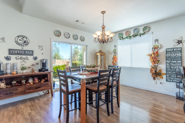 dining area with hardwood / wood-style flooring and a notable chandelier