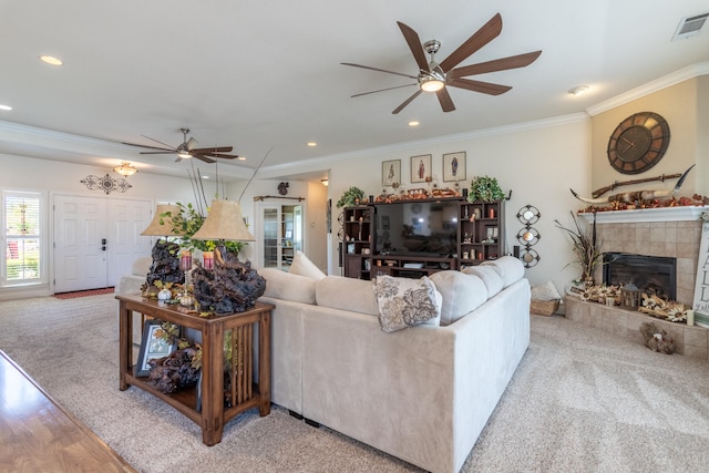 living room with light hardwood / wood-style flooring, ceiling fan, crown molding, and a tiled fireplace