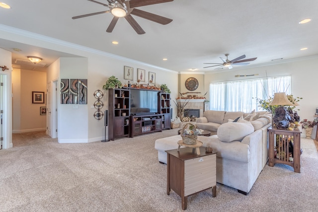 carpeted living room featuring ceiling fan, crown molding, and a tiled fireplace