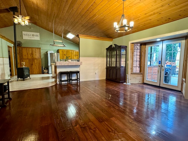 unfurnished dining area with ceiling fan with notable chandelier, wood ceiling, hardwood / wood-style floors, and a wood stove