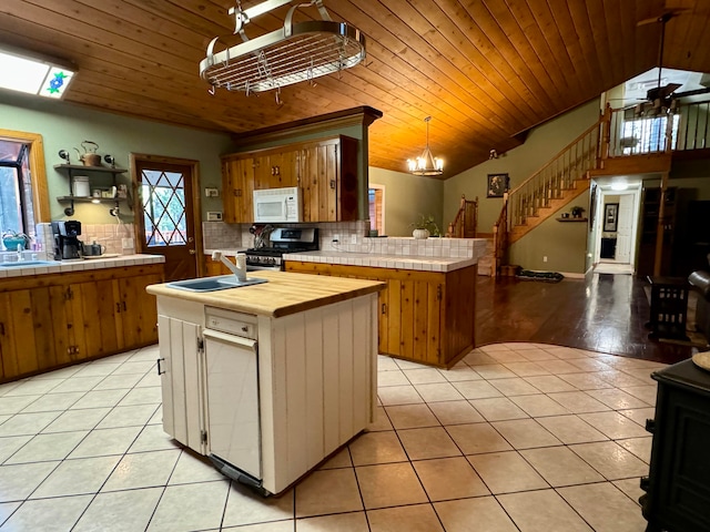 kitchen featuring hanging light fixtures, sink, light hardwood / wood-style flooring, a center island, and ceiling fan with notable chandelier