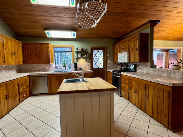 kitchen with stainless steel appliances, light tile patterned floors, tasteful backsplash, and sink