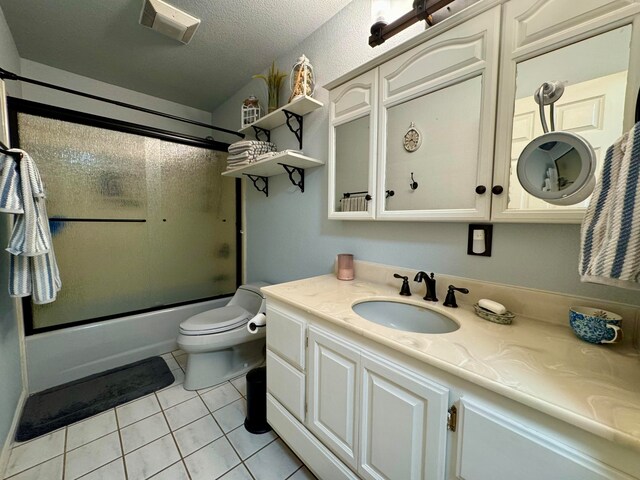 full bathroom featuring shower / bath combination with glass door, vanity, a textured ceiling, tile patterned floors, and toilet