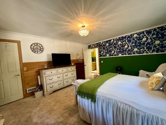 bedroom featuring ornamental molding, wooden walls, and light colored carpet