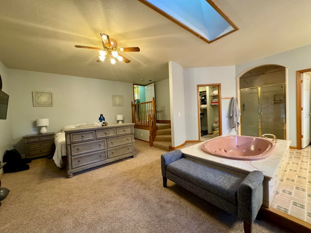 bedroom with a textured ceiling, a skylight, ceiling fan, and light colored carpet