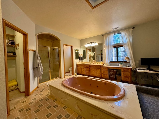 full bathroom with a textured ceiling, shower with separate bathtub, vanity, and toilet