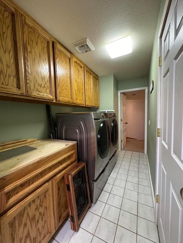 clothes washing area featuring cabinets, light tile patterned floors, separate washer and dryer, and a textured ceiling