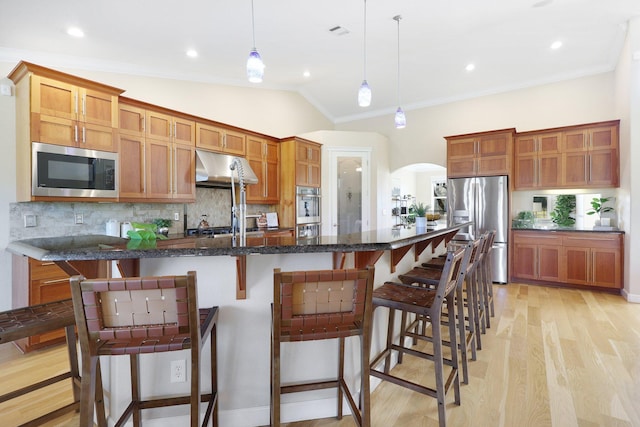 kitchen with a spacious island, lofted ceiling, decorative light fixtures, a breakfast bar, and appliances with stainless steel finishes